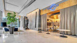 Een moderne lobby met een grote potplant, een beeld en een 'Caviar Russe' bord.