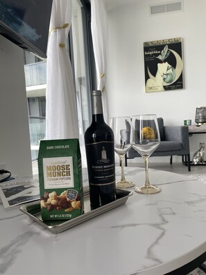 A dining table with a bottle of Robert Mondavi Cabernet Sauvignon, a box of Harry & David Moose Munch Premium Popcorn, and a wine glass.