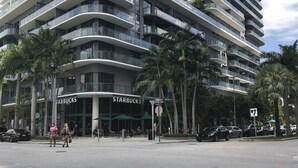 Ein modernes Hochhaus mit geschwungenen Balkonen und einem Starbucks im Erdgeschoss.