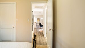 A hallway leading to a bedroom with a bed, a door, and a visible bathroom in the background. - Catskill Kaaterskill  Cabin Hot Tub FirePit Sauna (Lanesville)
