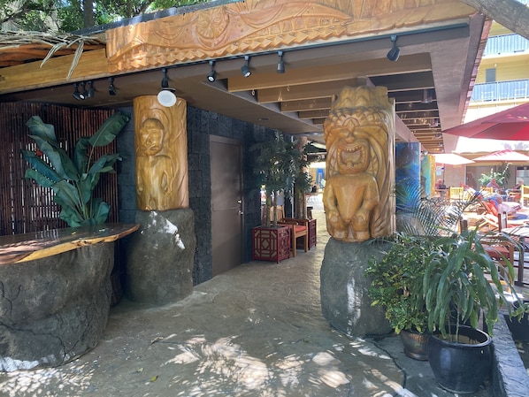 Une cour agrémentée de sculptures en bois, de plantes en pot et de mobilier d’extérieur.