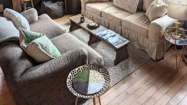 Un salon chaleureux avec un escalier en bois, un canapé beige, une table basse et une petite table d’appoint.