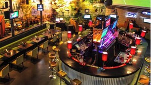 Un espace bar doté de plusieurs écrans, de différents types de sièges et d’un comptoir avec un barman.