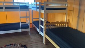 A room with bunk beds, wooden flooring, and orange walls.