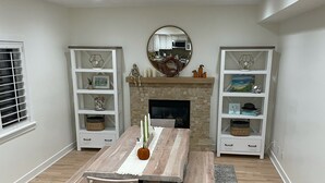 A dining area with a wooden table and benches, a fireplace, and built-in shelving with decorative items. - Beachy Home in Provo. Large deck with builtin hot tub, Fire pit, Palapa (Provo)