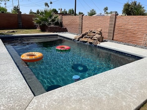 Una piscina rectangular con agua cristalina, rodeada por un muro de piedra y un muro de ladrillo.
