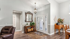 A spacious living area with hardwood flooring, a leather chair, a wooden console table with a mirror, and a dining table with chairs. - TROPICAL RETREAT WITH PRIVATE HEATED POOL-TAMPA BAY. (New Port Richey)