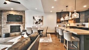 A modern kitchen with a large island, bar stools, and a fireplace.