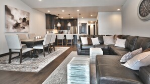 A modern living room with a dining area, leather sofas, and a large abstract painting.
