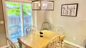 A dining area with a wooden table and four chairs, a pendant light, and a framed artwork on the wall. - Cheerful  NEW Executive Home with office-Meridian (Meridian)
