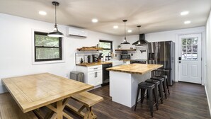 Une cuisine moderne avec un îlot central en bois, des appareils électroménagers en acier inoxydable et des tabourets de bar.
