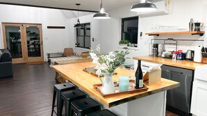 Une cuisine moderne avec un îlot central en bois, des tabourets de bar et un vase rempli de fleurs.