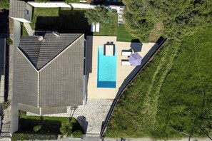 Vue aérienne d’une propriété résidentielle dotée d’une piscine, d’un patio couvert et d’un jardin aménagé.