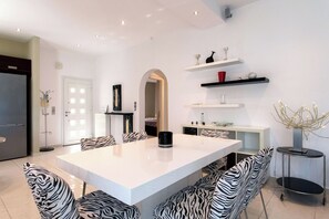 Une cuisine moderne avec un îlot central blanc, des chaises à motifs zébrés et une cafetière noire.
