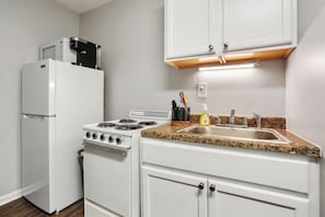 A compact kitchen with a white refrigerator, stove, and sink. - Serenity's Sanctuary| 1BR Near Bourbon & Frenchmen St (New Orleans)