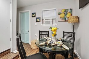 A dining area with a glass table, black chairs, and a vase with lemons. - Serenity's Sanctuary| 1BR Near Bourbon & Frenchmen St (New Orleans)