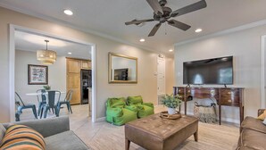 A spacious living room with a ceiling fan, a large flat-screen TV, and a dining area with a table and chairs. - Ocean Springs Home w/ Bikes < 1 Mile to Beach! (Ocean Springs)