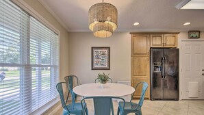 A kitchen with a round table, teal chairs, a hanging light fixture, and wooden cabinets. - Ocean Springs Home w/ Bikes < 1 Mile to Beach! (Ocean Springs)