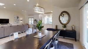 A modern living room with a dining area, a sofa, a TV, and a large mirror.