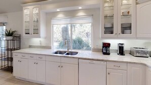A modern kitchen with white cabinetry, a large window, and built-in appliances.