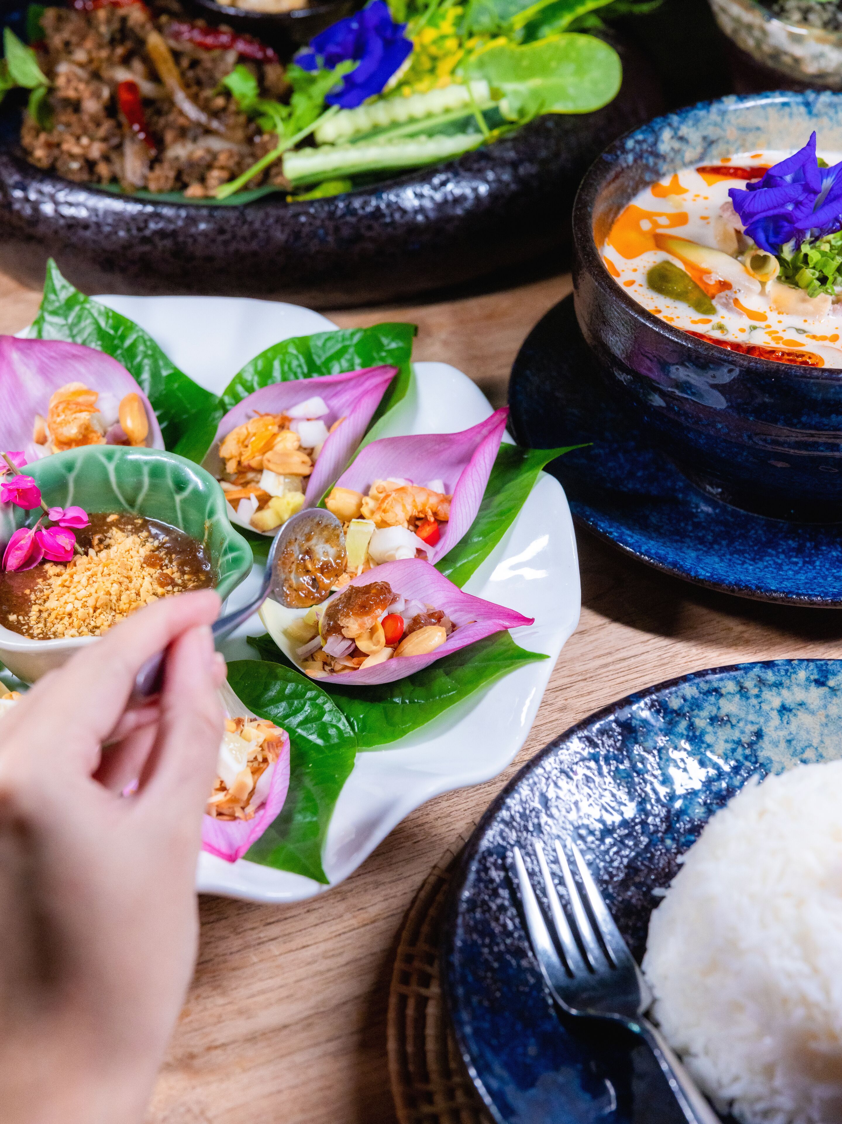 A variety of dishes including a bowl of soup, a plate with food in lotus leaves, and a bowl of rice.