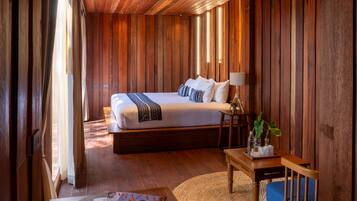 A bedroom with a large bed, bedside table, lamp, and a small plant.
