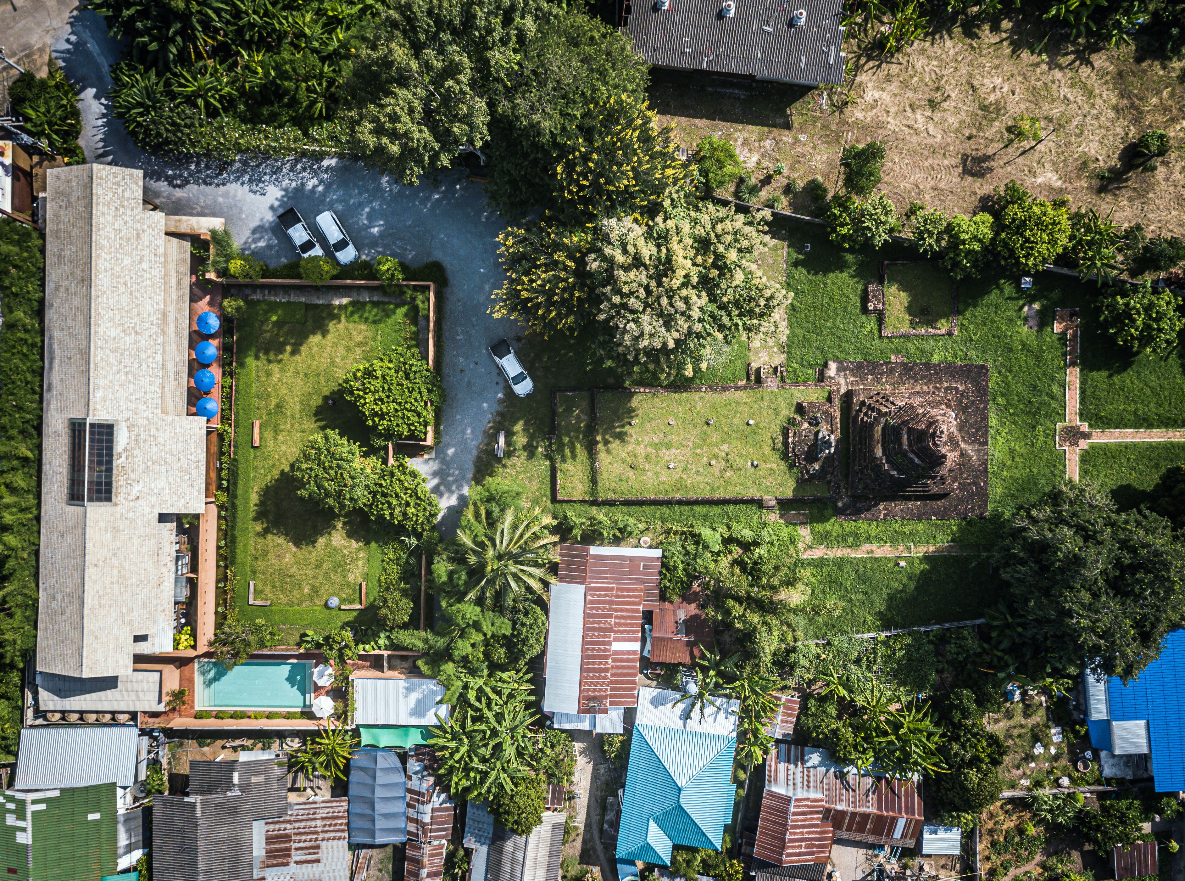 An aerial view of a residential area with a swimming pool, a garden, and a statue.