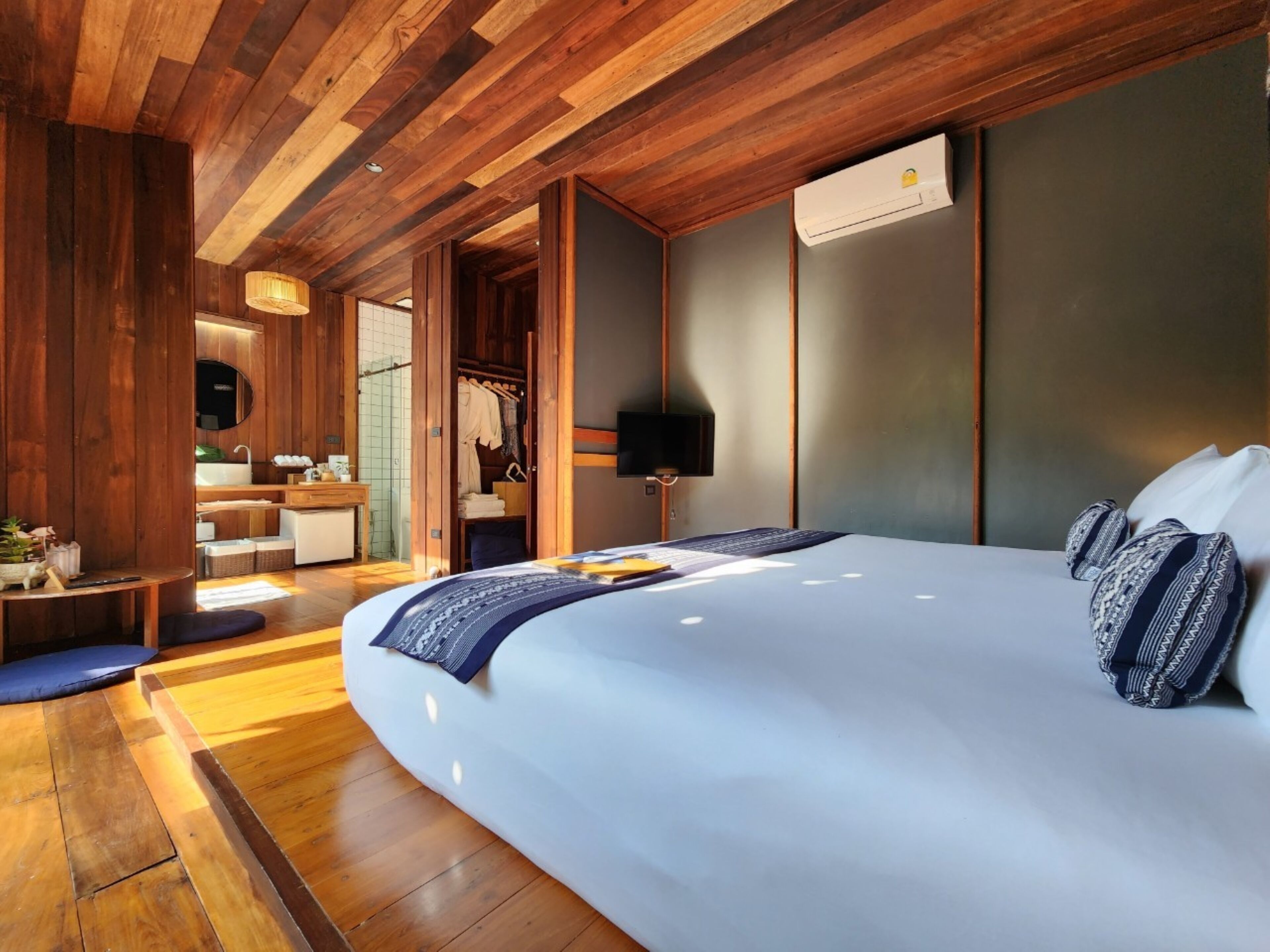 A modern bedroom with a large bed, wooden ceiling, and a walk-in closet.
