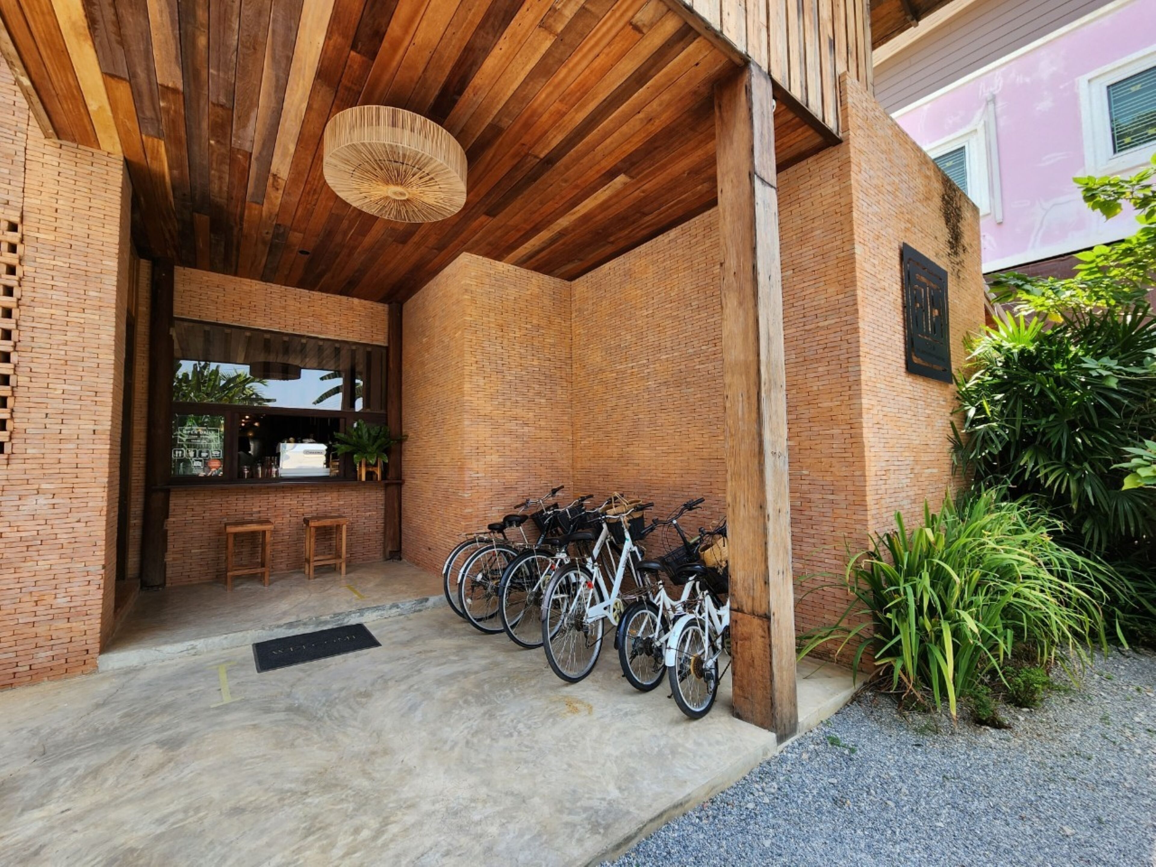 Un espacio al aire libre cubierto con pared de ladrillo, techo de madera y una fila de bicicletas estacionadas.