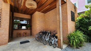 Un espacio al aire libre cubierto con pared de ladrillo, techo de madera y una fila de bicicletas estacionadas.