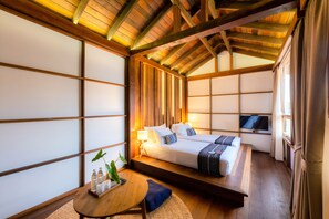 Ein traditioneller japanischer Raum mit Tatami-Boden, einem niedrigen Holzbett, einem kleinen Tisch mit Tablett und einem Fernseher an der Wand.