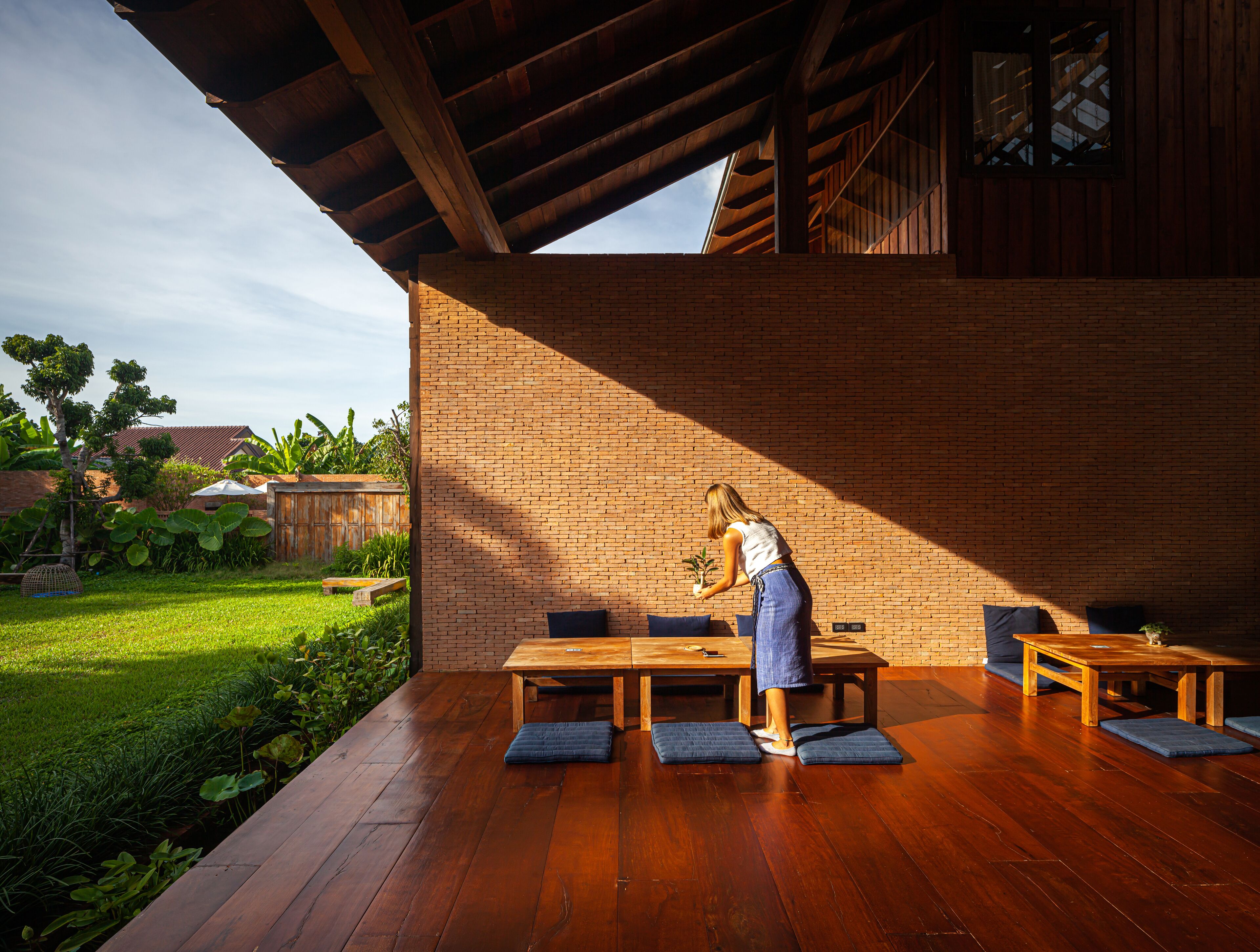 An outdoor patio with wooden furniture and a brick wall.