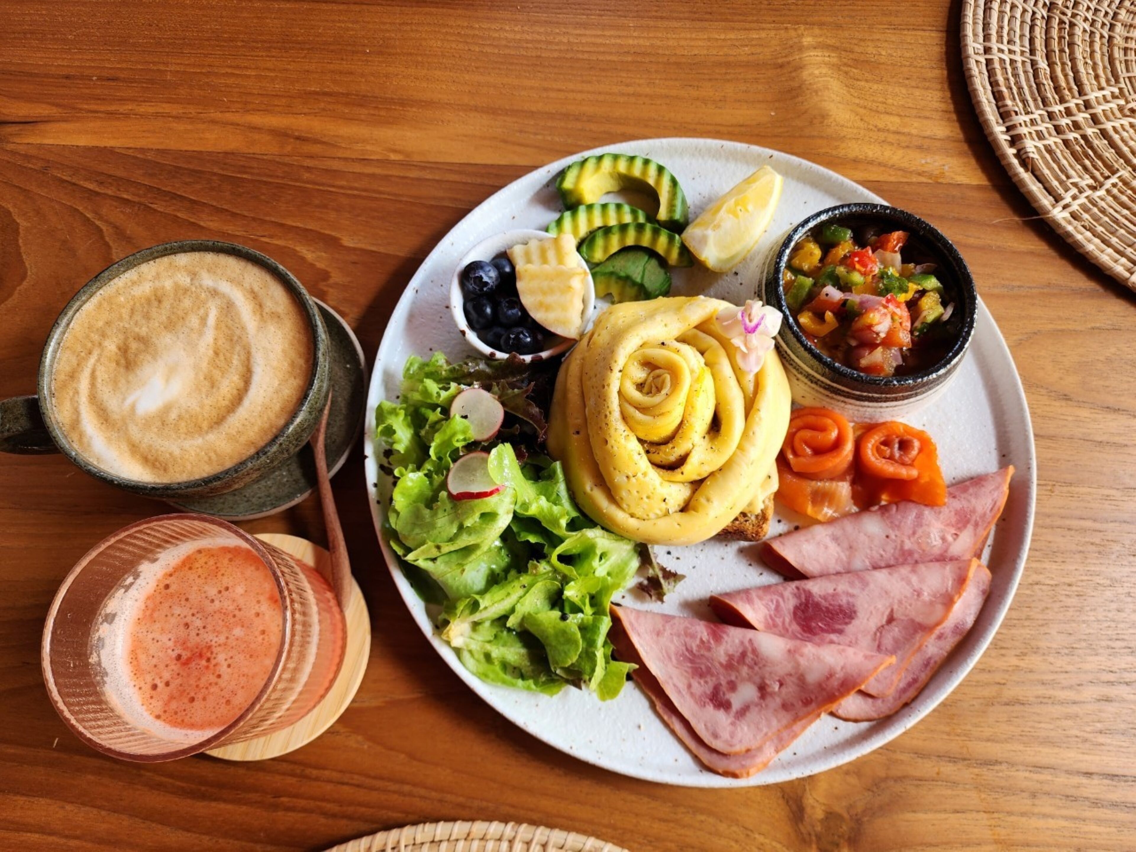 A plate with various foods including a salad, sliced ham, and a bowl of vegetables.