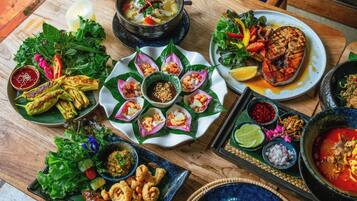 A variety of dishes on a wooden table, including grilled meat, seafood, and vegetables.