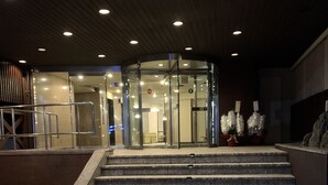 Una entrada moderna con puertas de vidrio, un conjunto de escalones de piedra y piso de baldosas.