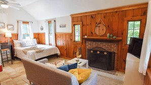 A cozy room with a bed, a sofa, a fireplace, and a television. - Walk 1/10 Mile to Lecount Hollow Beach! (Wellfleet)