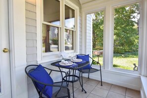 A covered patio with a table set for two, featuring blue chairs and a white tablecloth.