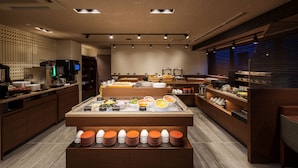 A modern breakfast area with a central counter displaying various food items and a selection of plates and bowls. - Hotel Grand Consort Naha (Naha)