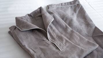 A neatly folded grey shirt on a white bed.