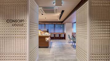 A modern lounge area with a patterned wall, a reception desk, and seating.