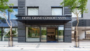The exterior of Hotel Grand Consort Naha with a modern design, large windows, and two trees in front. - Hotel Grand Consort Naha (Naha)