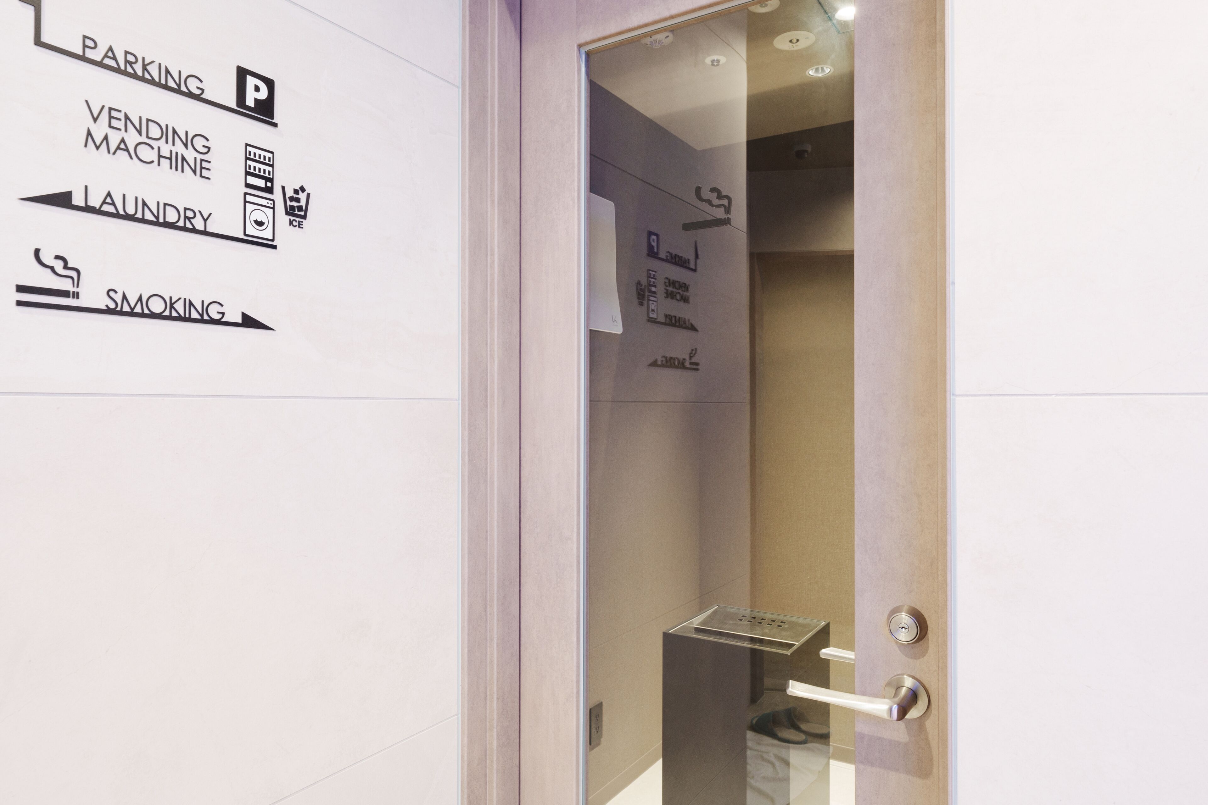 A hotel entrance with a sign indicating amenities such as parking, vending machine, laundry, and smoking.