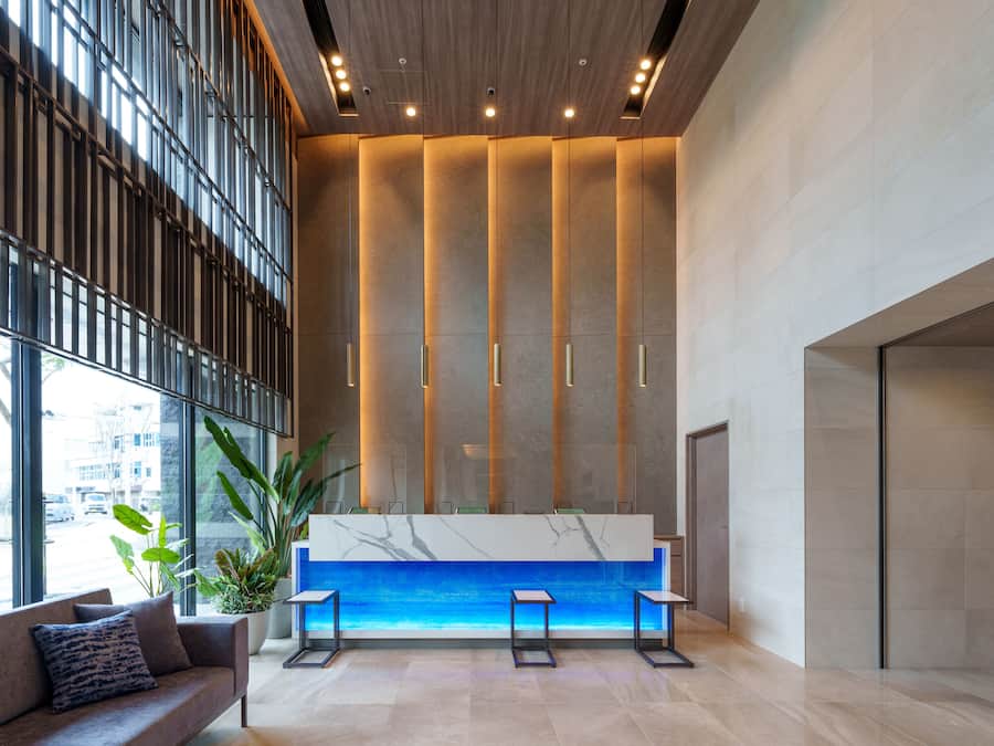 A modern reception area with a marble counter, seating, and large windows.