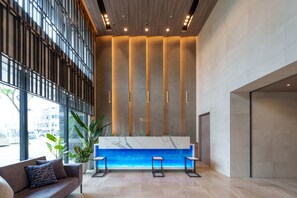 A modern reception area with a marble counter, seating, and large windows. - Hotel Grand Consort Naha (Naha)
