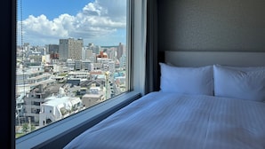 A hotel room with a large window offering a city view. - Hotel Grand Consort Naha (Naha)