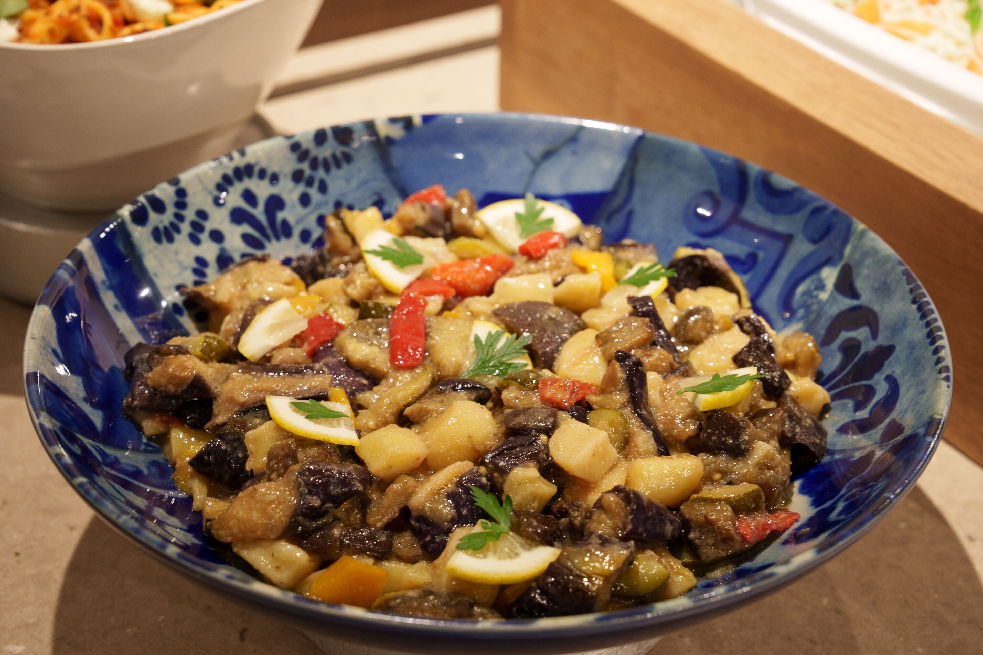 Un tazón de estofado con verduras y carne, adornado con perejil y rodajas de limón.