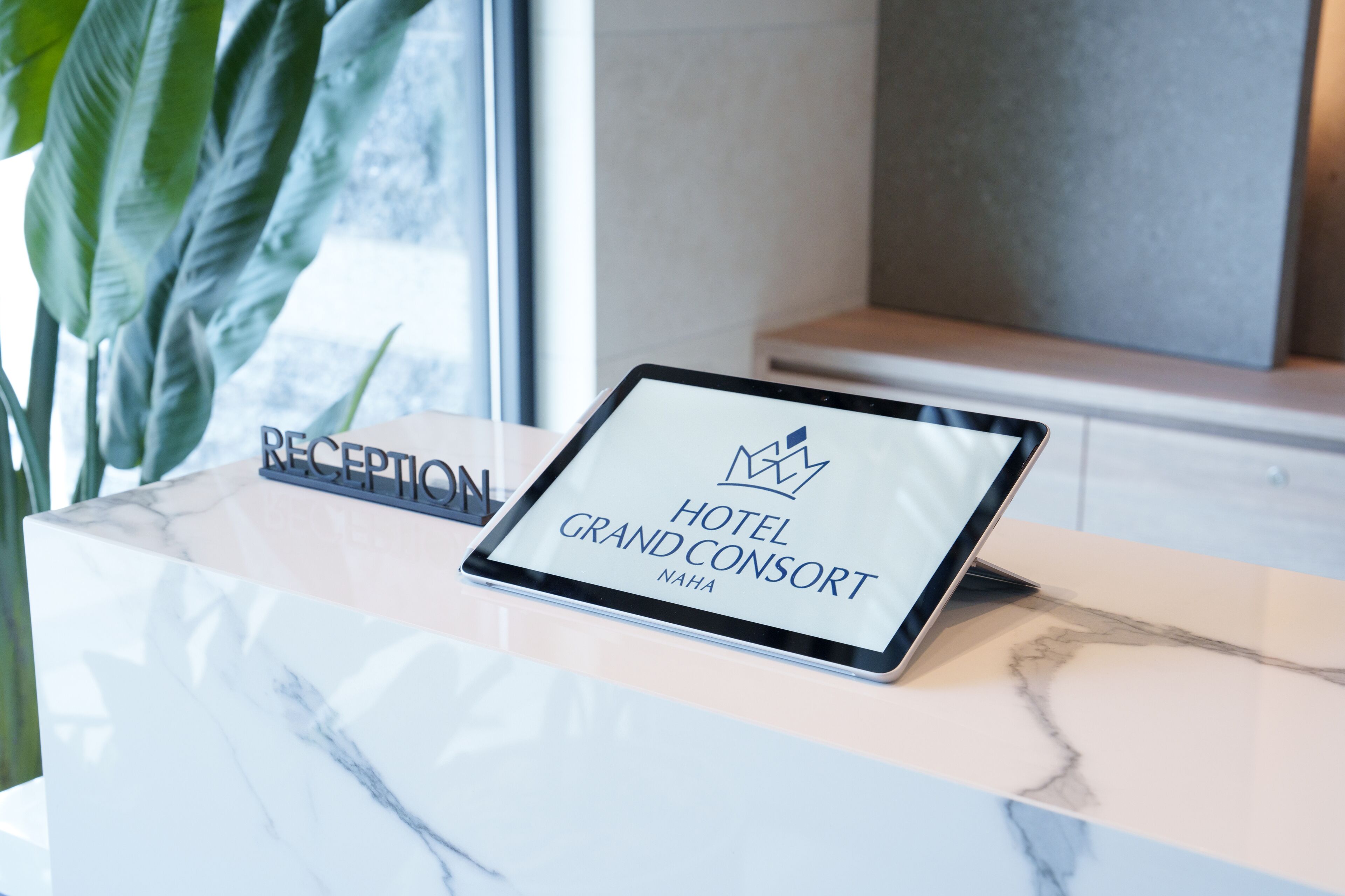 A reception desk with a digital screen displaying the hotel's name and logo.