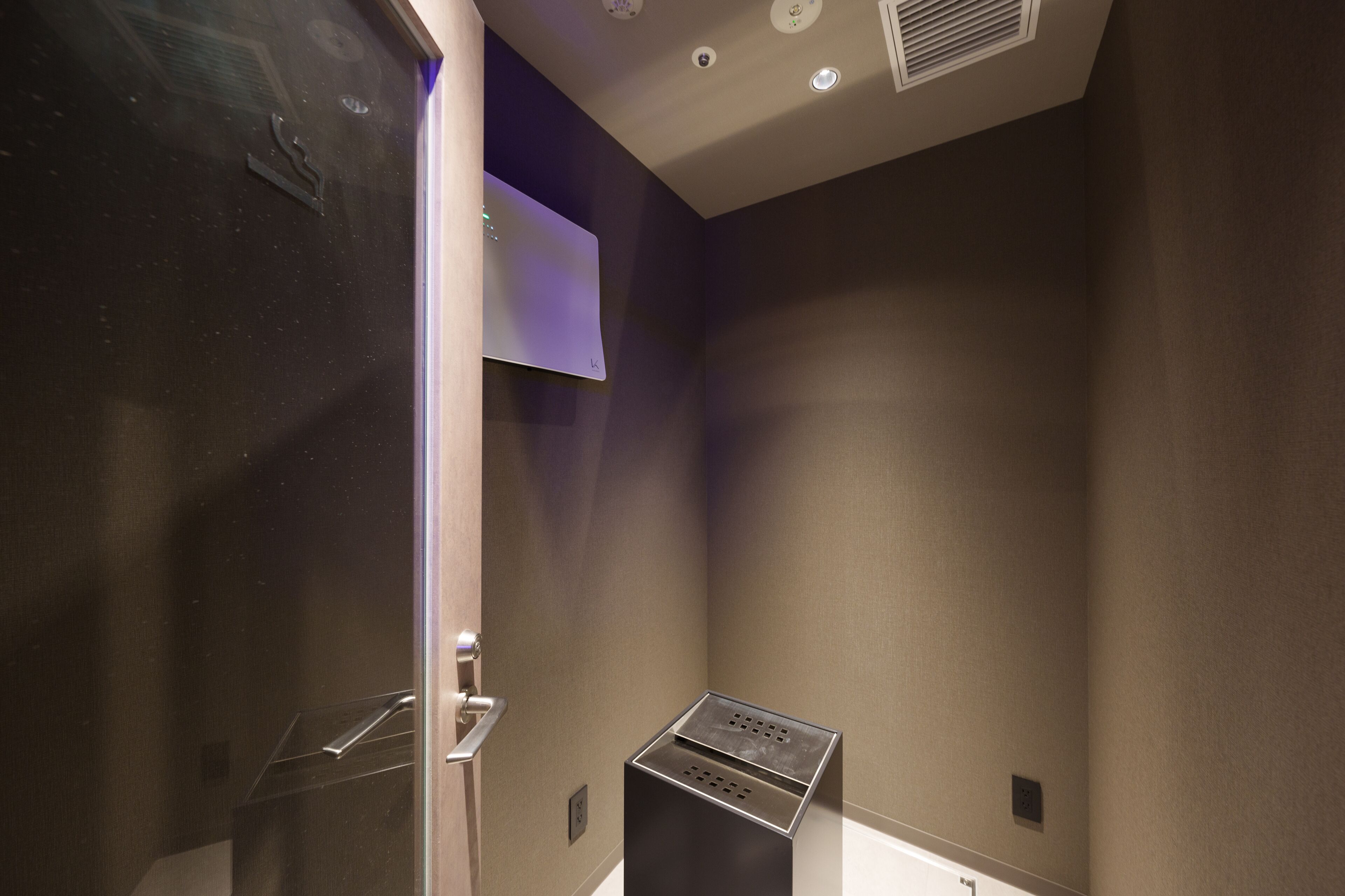 Un baño moderno con separador de vidrio, lavamanos metálico e iluminación empotrada en el techo.