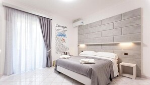 Een moderne slaapkamer met een groot bed, een grijze hoofdbord en een wandlamp.