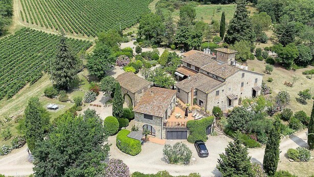 Une propriété rurale avec une maison en pierre entourée de vignes, une allée et une voiture.